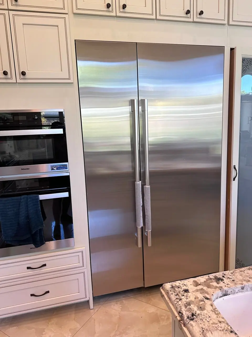 Built-in side-by-side refrigerator beside Miele wall ovens — repaired by Marian Appliance Repair